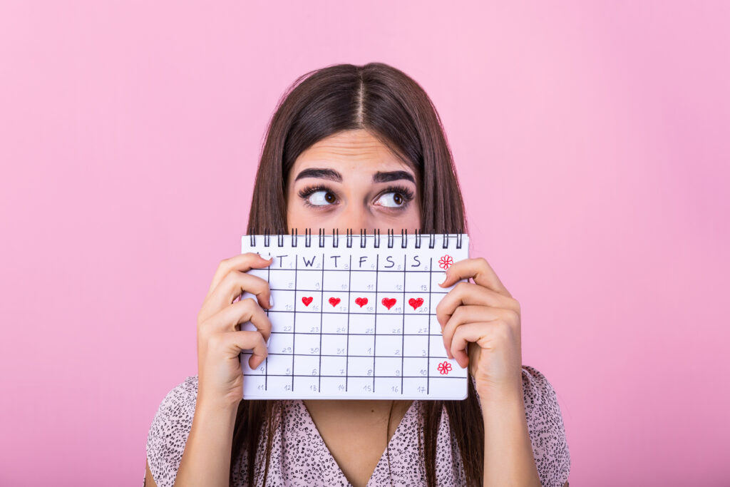 young girl hiding menstrual periods calendar looking away